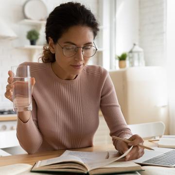 woman looking through paperwork and drinking water