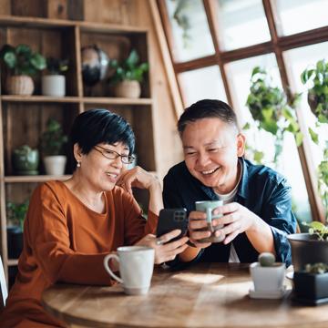 couple drinking tea together and looking at information on wife’s phone